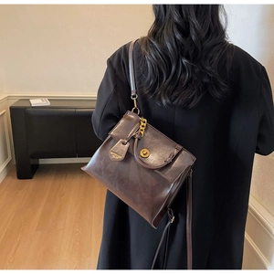 Detail of vintage brown leather backpack with gold clasp and decorative metal chain