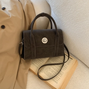 Detail of dark brown vintage matte shoulder bag with metallic clasp on a book