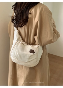 Detailed close-up of a cream canvas tote bag with brown leather patch and drawstring side