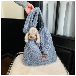 Detail of light blue fleece tote bag with brown leather tag and cute plush bunny charm