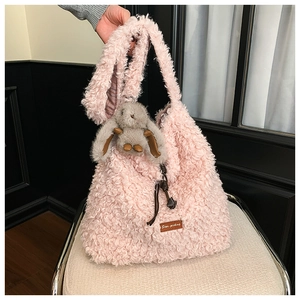Close-up of pink sherpa tote bag with plush bunny charm and Star-picking leather tag