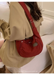 Detail of red canvas crescent bag with side zippers and adjustable metal buckle