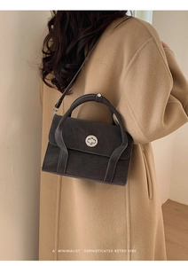 Back view of minimalist dark grey frosted satchel with silver buckle on camel coat