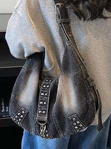 Vintage dark denim tote bag with silver studs and adjustable strap in a street style look