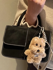 Chic black flap handbag with white stitching and cute brown plush puppy charm