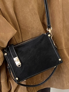 Vintage black crossbody bag with white stitching and gold metal clasp on a female model