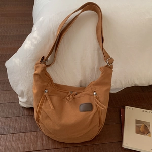 Detailed macro view of camel canvas tote bag with front zippers and adjustable shoulder strap