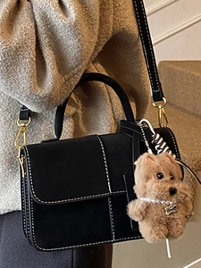 Chic black faux suede crossbody bag with contrast stitching and plush dog charm