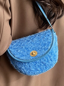 Sacoche bleue en fausse fourrure avec fermoir doré sur un manteau d'hiver