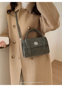 Detail of dark gray retro leather handbag with silver lock shown on a model