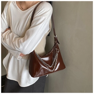 Détail du sac à bandoulière marron foncé brillant avec chaîne argentée et bandoulière