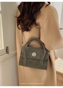 Detail of dark olive green textured leather handbag with a silver circular rotary lock