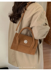 Close-up of a brown retro leather handbag with a silver circular twist lock and handle