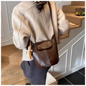 Detail einer braunen Leder-Eimertasche mit einzigartigen bunten Holzperlen-Anhängern