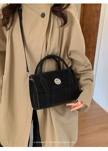 Detail of black suede bag with silver metal twist lock worn over a khaki trench coat