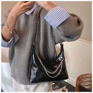 Détail du sac sous le bras en noir brillant avec double chaîne argentée et sangle
