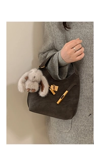 Dettaglio borsa hobo in camoscio marrone con fibbia dorata e ciondolo a forma di coniglio