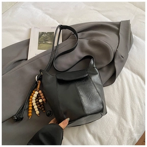 Detail einer schwarzen matten Eimertasche mit Perlenquaste und genarbter Lederstruktur