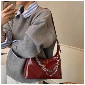 Vue détaillée du sac sous le bras brillant bordeaux avec chaîne argentée sur modèle