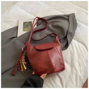 Detailansicht der burgunderroten Beuteltasche mit Holzperlen auf weißem Hintergrund