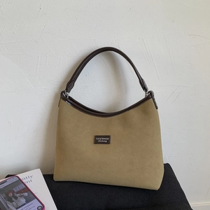 Close-up of khaki suede shoulder bag with brown leather contrast trim and metal ring hardware