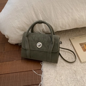 Detail of vintage olive green faux leather handbag with silver round rotating metal lock