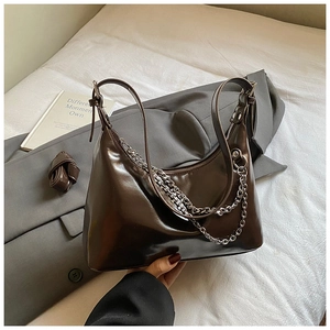 Détail du sac en cuir verni marron foncé avec chaîne argentée et bandoulière