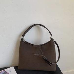 Detail of dark coffee suede crossbody bag featuring silver hardware and adjustable strap