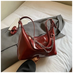 Détail du sac sous le bras rouge foncé brillant avec chaîne argentée et boucle ajustable
