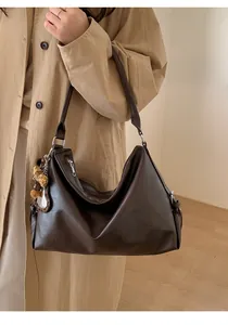 Détail d'un sac cabas en similicuir marron foncé avec un porte-clé pompon motif léopard