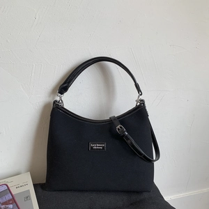 Detail of minimalist black matte crossbody bag featuring elegant brand logo and leather strap