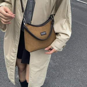 Detail of retro tan suede crossbody bag with brown leather trim and metallic buckle