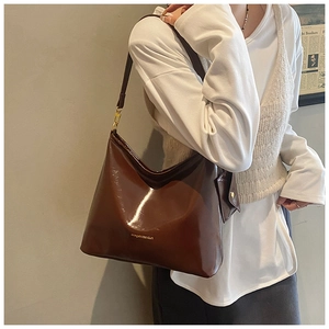 Detail of a shiny dark brown hobo bag with a matching mini pouch on a chic shoulder strap