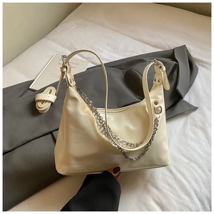 Détail d'un sac sous le bras beige avec chaîne argentée et bandoulière amovible