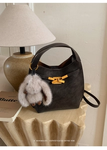 Dettaglio mini borsa a secchiello retrò con fibbia dorata e ciondolo a coniglietto