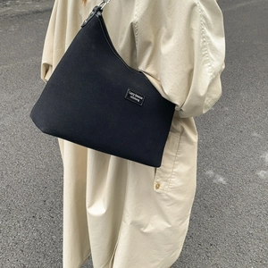 Detail of minimalist black canvas underarm bag with Lazy Breeze woven brand label