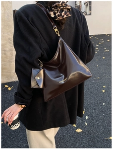 Detail of glossy dark brown leather hobo bag with matching mini envelope pendant charm