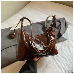 Détail d'un sac à bandoulière en simili cuir marron foncé avec chaîne en métal argenté