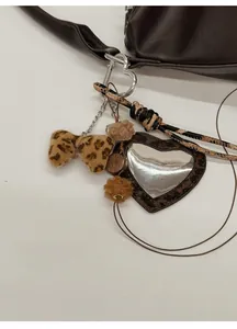 Détail d'un porte-clés nœud en peluche léopard avec miroir cœur et pompon marron doux