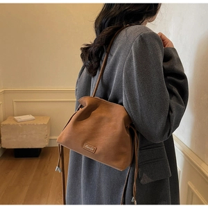 Detail of a brown pleated cloud bag with soft matte leather and drawstring on a model