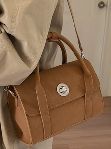 Vintage brown crossbody bag with silver twist lock and leather strap in studio setting