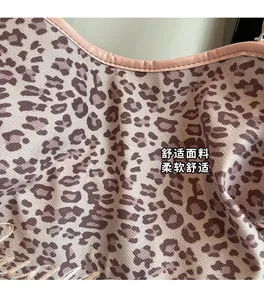 Detailed close-up of leopard print fabric with pink leather trim and golden embroidery