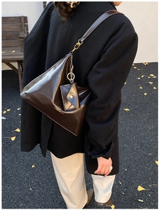 Detail view of deep brown glossy leather tote bag with stylish mini envelope pouch attachment