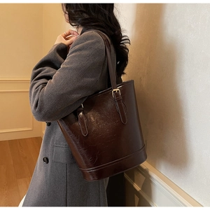 Detail view of large brown oil wax leather tote bag with vintage texture and golden buckle