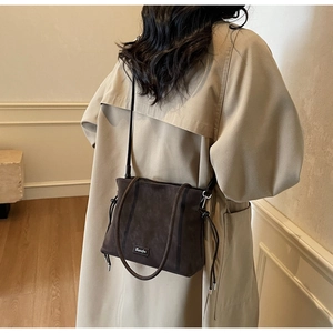 Detail view of dark coffee bucket bag with matte suede texture and adjustable side drawstrings