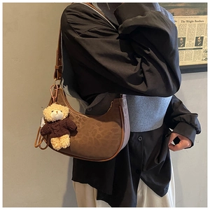 Detail of brown leopard print baguette bag with a cute teddy bear plush charm