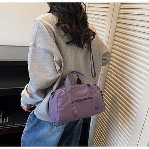 Detail of purple nylon tote bag featuring a rear zipper pocket and woven handles
