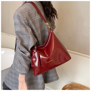Macro shot of dark red patent leather tote bag with gold branding and small coin purse