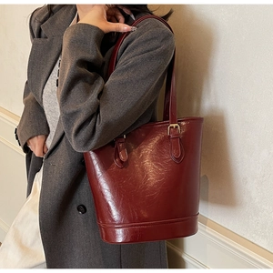 Detailed macro of dark red vintage tote bag with glossy leather texture and gold buckle