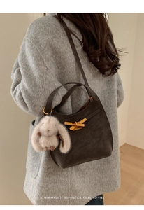 Dettaglio borsa in pelle marrone con chiusura dorata e ciondolo coniglio morbido